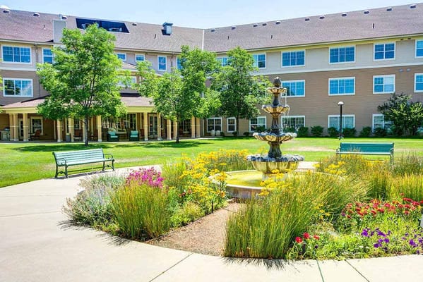 Fountain surrounded by vibrant flowers and benches in courtyard