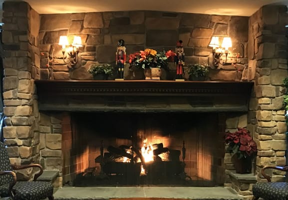 Stone fireplace with a warm fire and seasonal decor