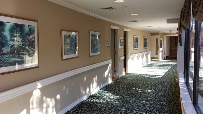 Brightly lit hallway with framed artwork and patterned carpet