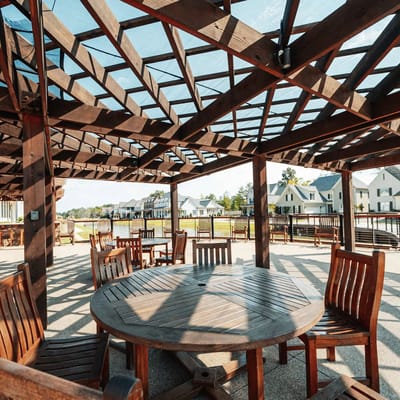 Outdoor shaded seating area with wooden tables and chairs