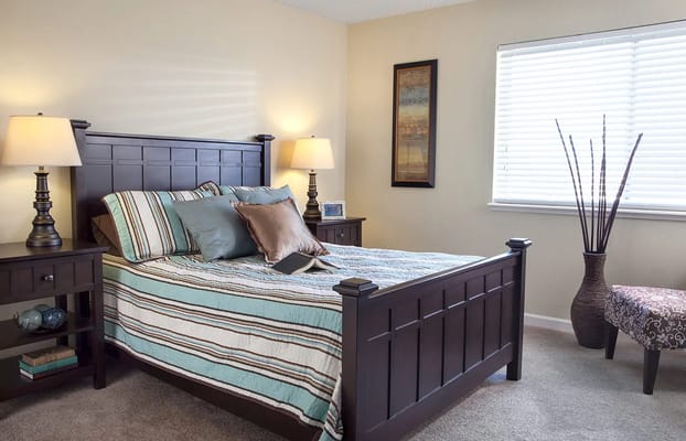 Spacious bedroom with a wooden bed frame and decorative pillows