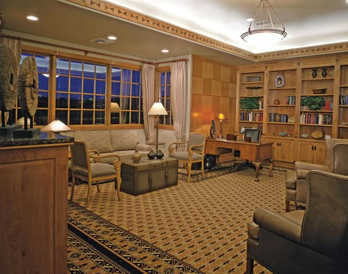 A cozy lounge with a sofa, chairs, and bookshelves in a senior living facility.