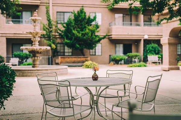Table and chairs with a flower vase in an outdoor dining area.