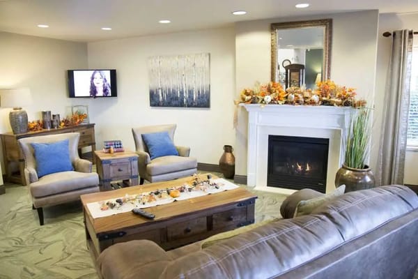 A cozy living room with comfortable seating, fireplace, and autumn decor.