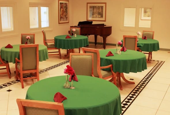 Bright dining room with green tables and piano