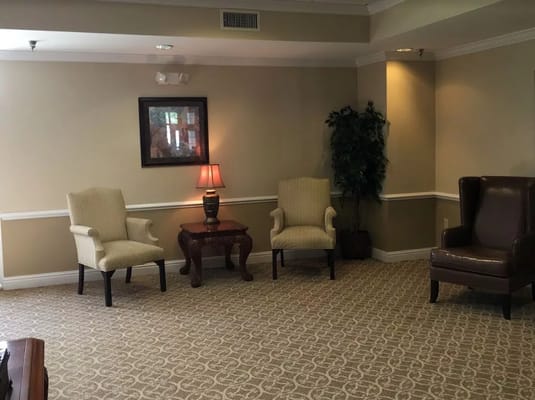 A cozy living area featuring two armchairs, a lamp, and a decorative plant.