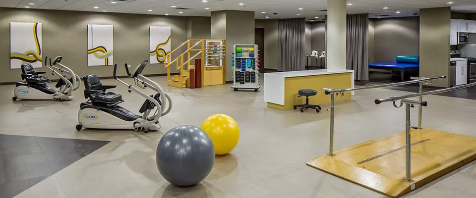 A spacious therapy gym featuring exercise equipment and therapy tools.