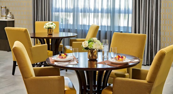 Cozy dining setup with yellow chairs and floral centerpieces