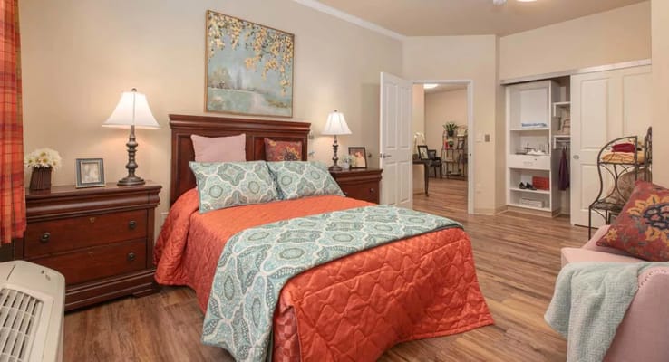 A well-decorated bedroom featuring a bed with colorful bedding and soft lighting.