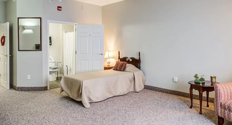 Bright and spacious bedroom with a bed, lamp, and small table.