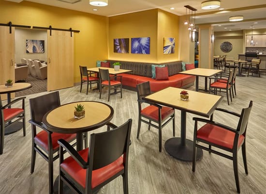 Cozy lounge area with tables and chairs in a senior living facility