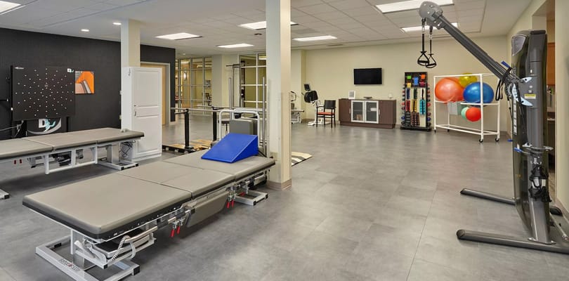 A therapy room with exercise equipment and therapy tables