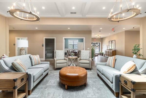 Cozy living room with light-colored furniture and a round ottoman
