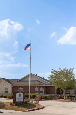 Entrance view of The Heritage of Meyerland with American flag