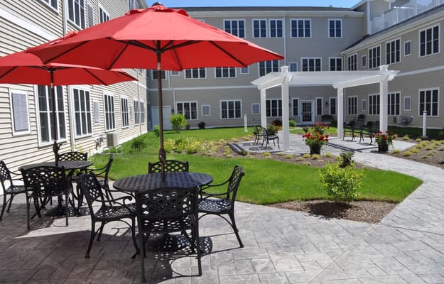 Outdoor patio with black tables and red umbrellas in a courtyard