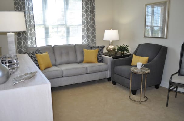 Comfortable living room with a gray couch and armchair, accented by yellow pillows.