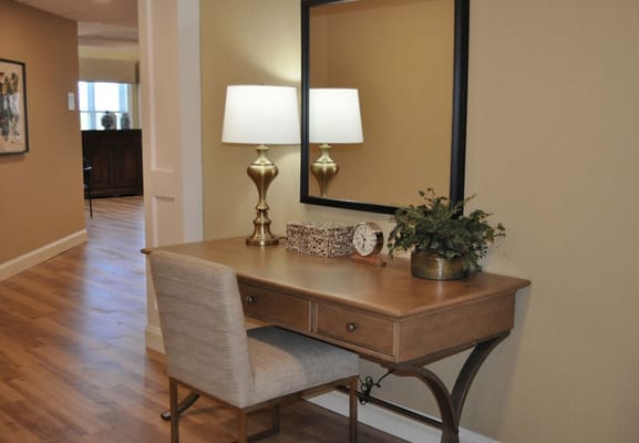A well-decorated desk with a lamp, clock, and plants.