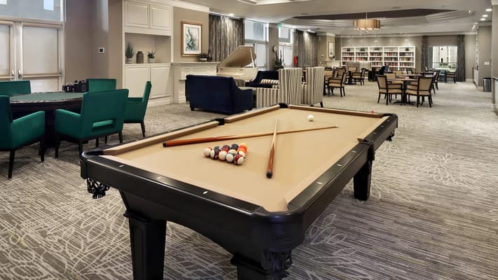 Billiards table with cues and balls in a senior living facility lounge