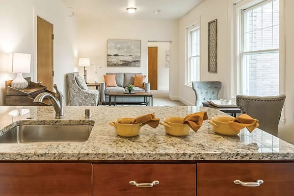 Bright living room and kitchen with granite countertop at The Kenney.