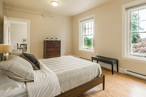 A well-furnished bedroom with a bed, dresser, and seating area