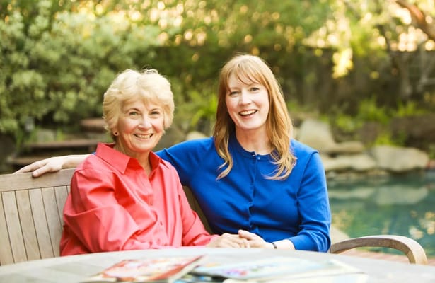 Two women smiling together by a pool