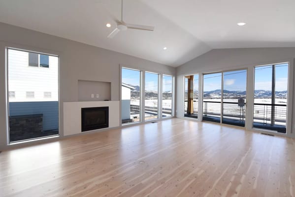 A spacious living room with large windows and a fireplace.