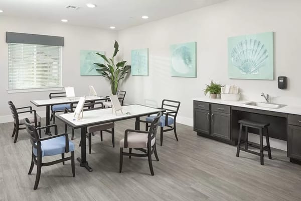 Light-filled common area with tables and chairs for activities