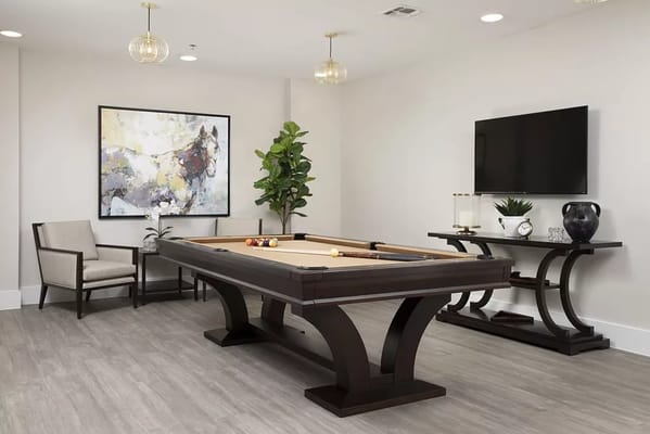 Billiards table in a modern recreation room with seating and decor.