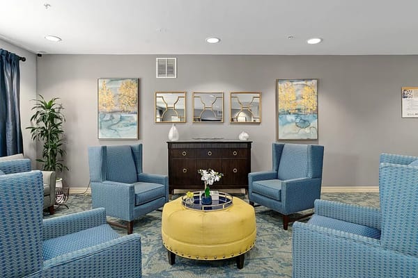Comfortable blue armchairs and a yellow ottoman in a lounge area