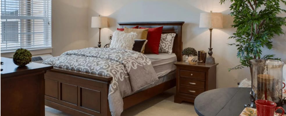 Well-furnished bedroom with a bed, nightstand, and decorative plants.