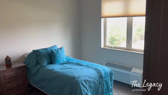A well-furnished bedroom with a blue bedspread and window