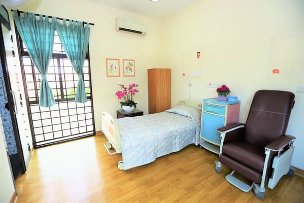 Interior of a private resident room with bed and chair