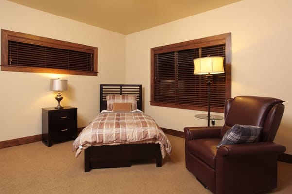 A well-furnished bedroom with a bed, chair, and lamp.