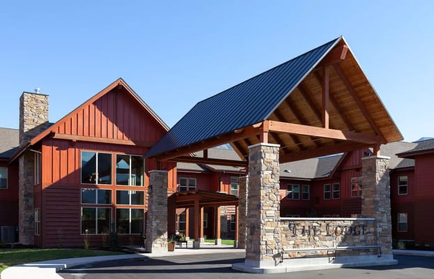 The entrance of The Lodge at North Ogden with a wooden canopy and stone pillars.