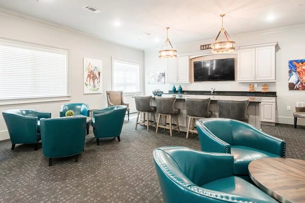 Cozy lounge area featuring teal chairs and a bar.