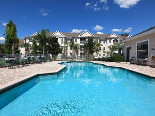 Outdoor pool area with seating and building in background