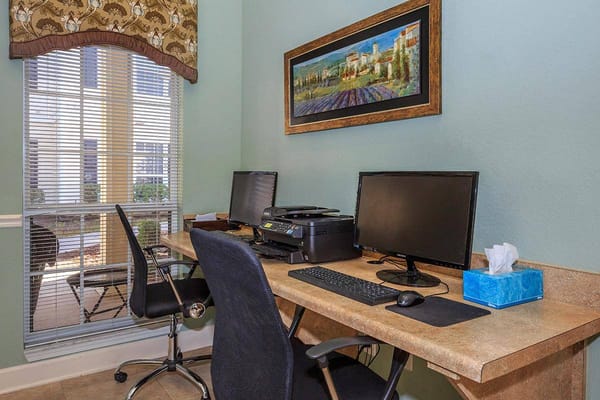 Workstations with computers and printer in a well-lit room