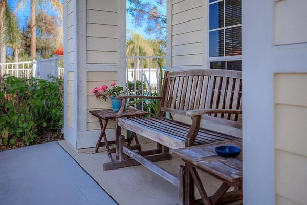 Wooden bench and small table with flowers in a sunny outdoor area