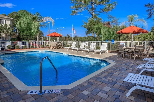 Swimming pool surrounded by lounge chairs and umbrellas.