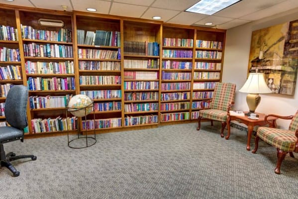 Cozy library with bookshelves, reading chairs, and a globe.
