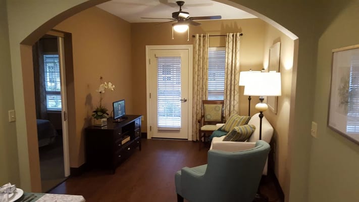 Spacious living room with blue armchair and TV