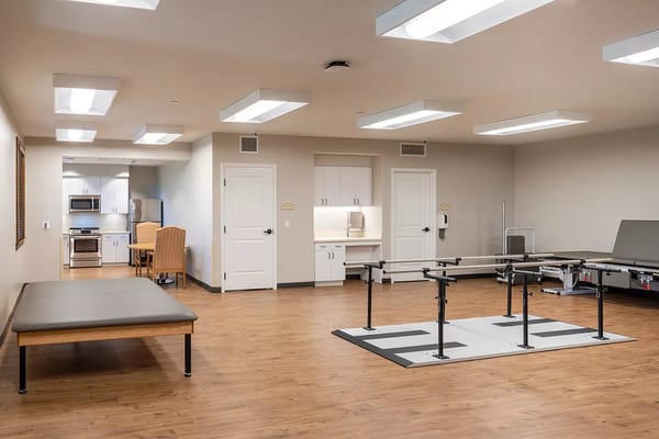 A spacious therapy room with rehabilitation equipment and a kitchenette.