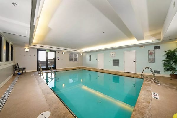 Indoor pool area with lounge chairs and bright lighting