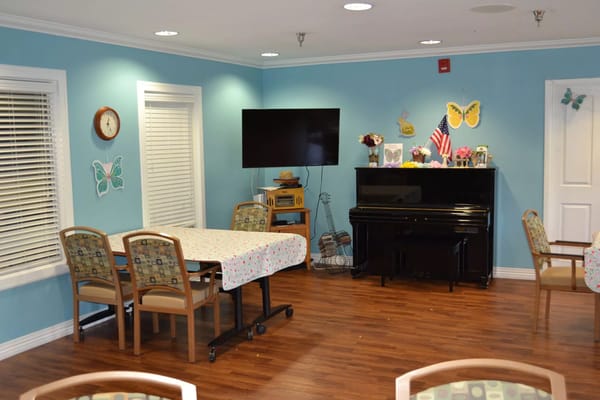 Cozy common room with a piano and decorated walls at The Palmettos of Charleston.