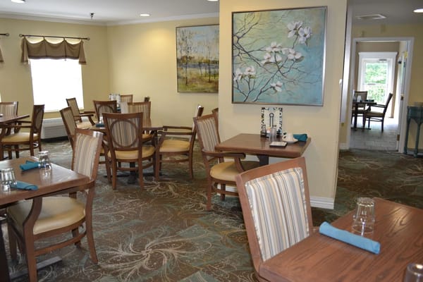 Bright and welcoming dining area with wooden tables and art on the walls.