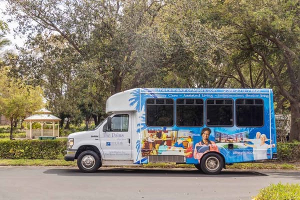 Shuttle bus with The Palms of Fort Myers branding parked near a gazebo