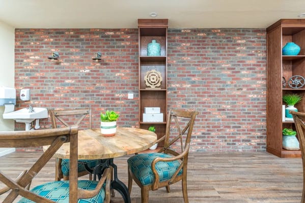 A cozy common area featuring a wooden table and brick wall.