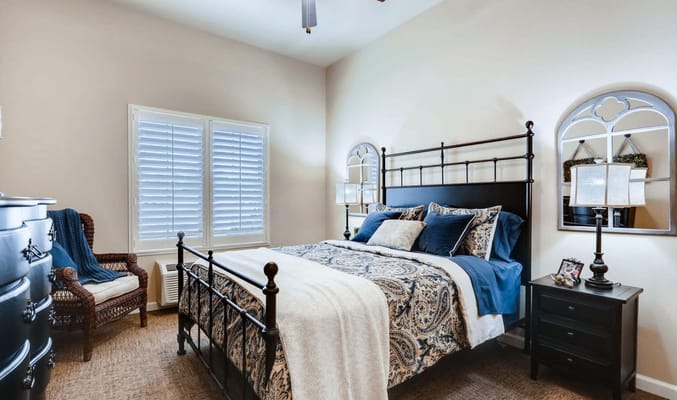A well-decorated bedroom featuring a metal bed frame, decorative pillows, and warm lighting.