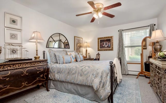 A cozy bedroom with a bed, decorative pillows, and bedside lamp.
