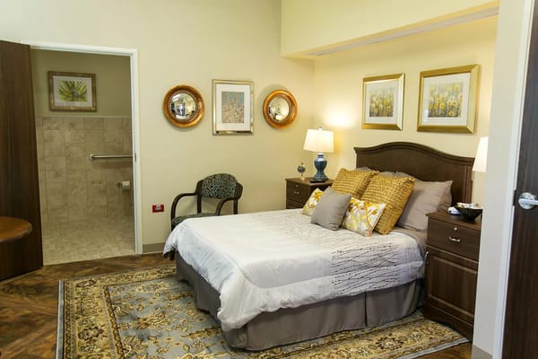 A cozy bedroom with a bed, decorative pillows, and artwork